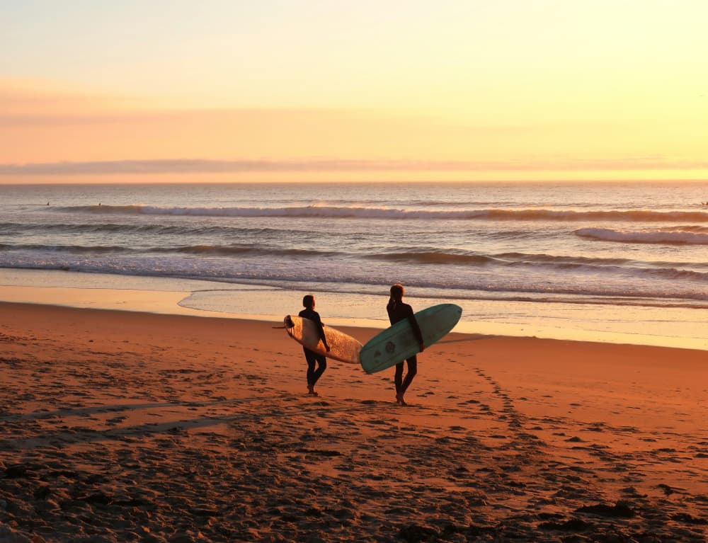 Surfers walking along Canggu beach at sunset