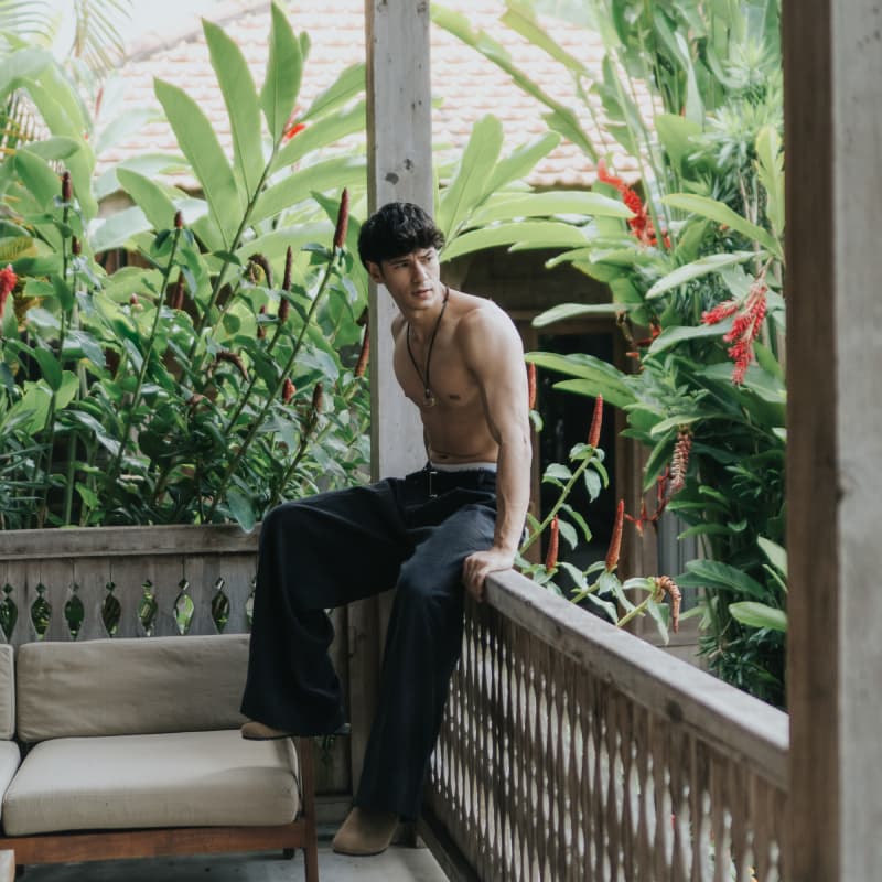 Guest on teakwood veranda balcony surrounded by lush tropical garden at Rimbun Villa Canggu