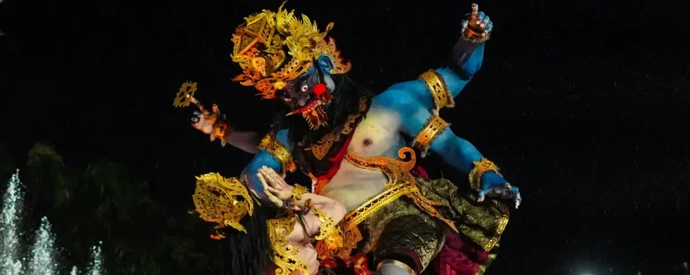 Two large ogoh-ogoh statues in a symbolic battle, set against a dark sky.