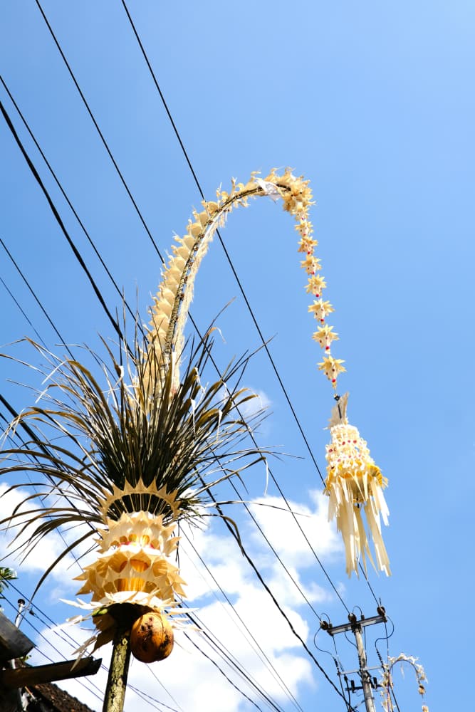 Traditional Balinese Penjor for Galungan festival against a clear blue sky.